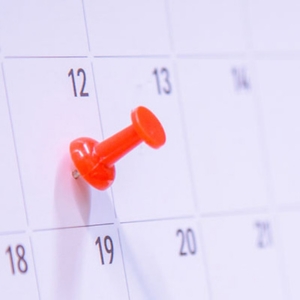 Termine-Quadrat Ein Foto von einer Pinnnadel, die in einem Kalender steckt